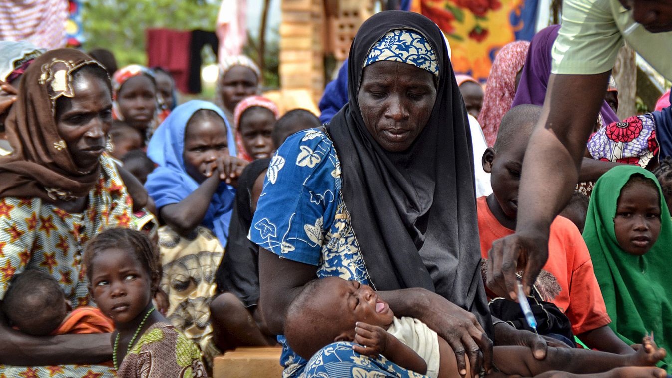 A woman carries her baby as a paramedic official administers an injection at an internal displaced person's camp, after they were rescued with other abductees from Boko Haram, near Mubi