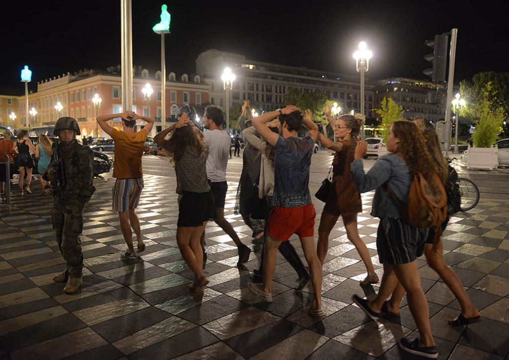 People cross the street with their hands on thier heads as a French soldier secures the area after at least 60 people were killed in Nice when a truck ran into a crowd celebrating the Bastille Day national holiday