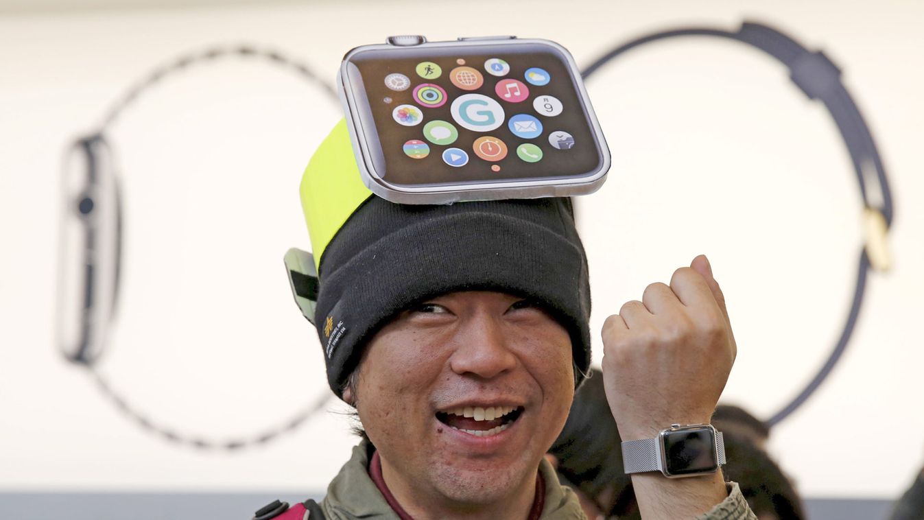 A man wearing cardboard hat depicting an Apple Watch, reacts as he tries on the watch after it went on display the Apple Store at Tokyo's Omotesando shopping district 
