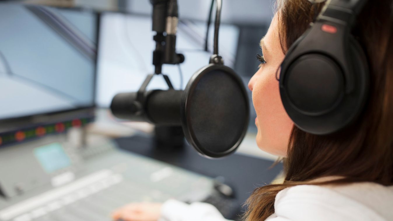 Jockey Wearing Headphones While Using Microphone In Radio Studio