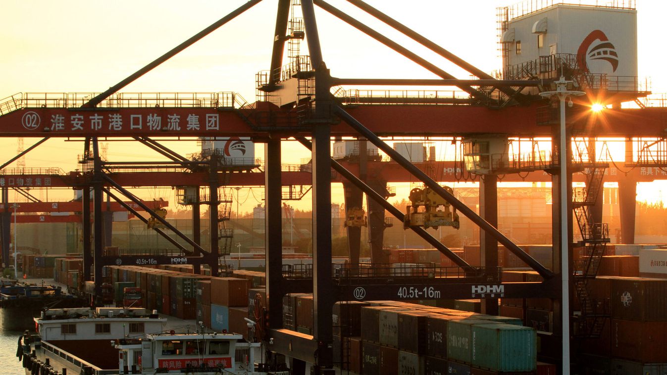 Cargo ship is seen next to containers at a river port during sunset in Huaian