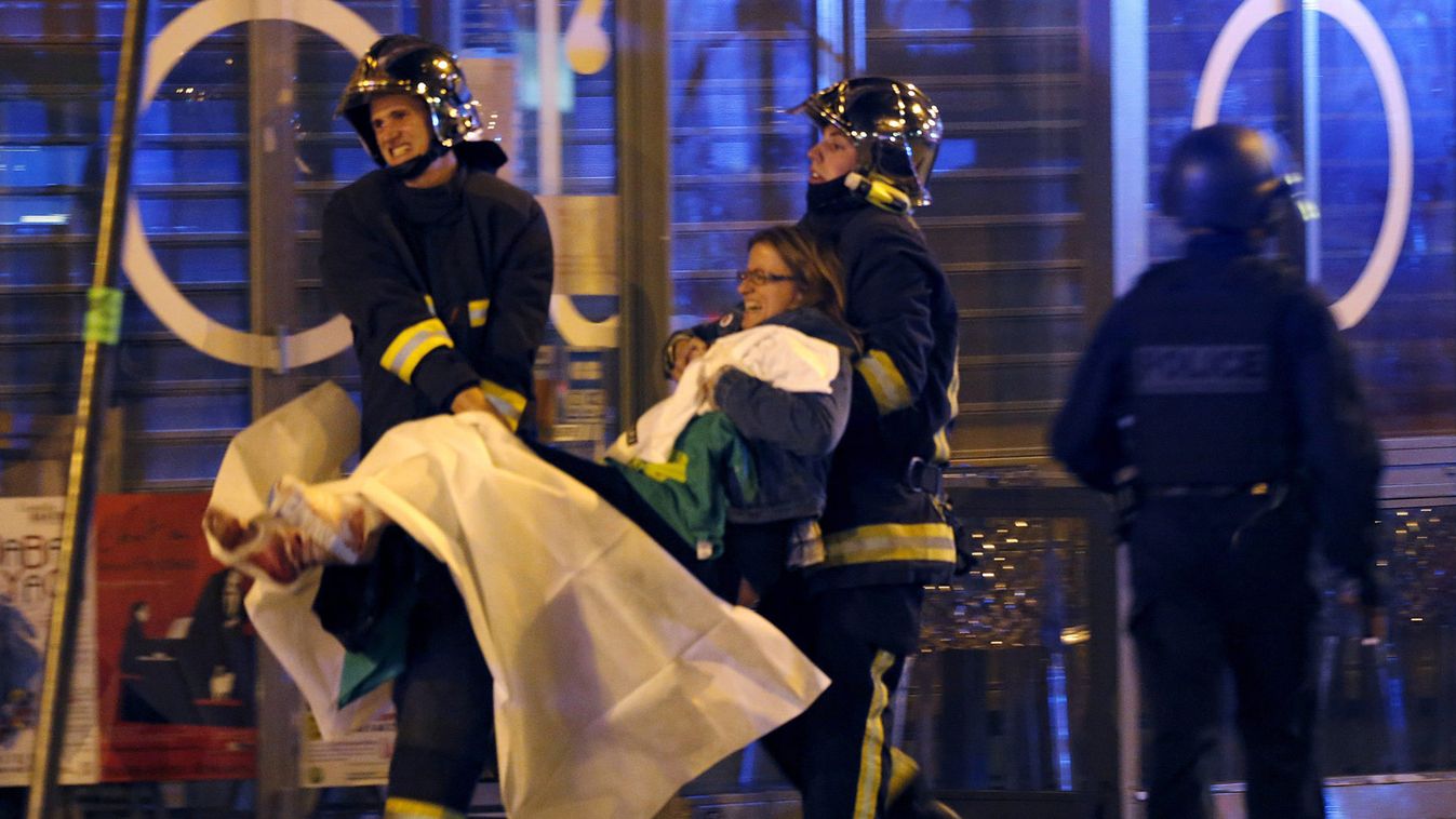 French fire brigade members aid an injured individual near the Bataclan concert hall following fatal shootings in Paris