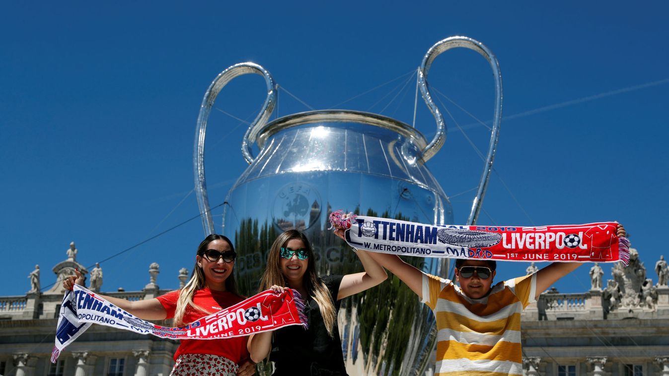 People pose next to a giant replica of the UEFA Champions League trophy that is displayed outside the Royal Palace in Madrid