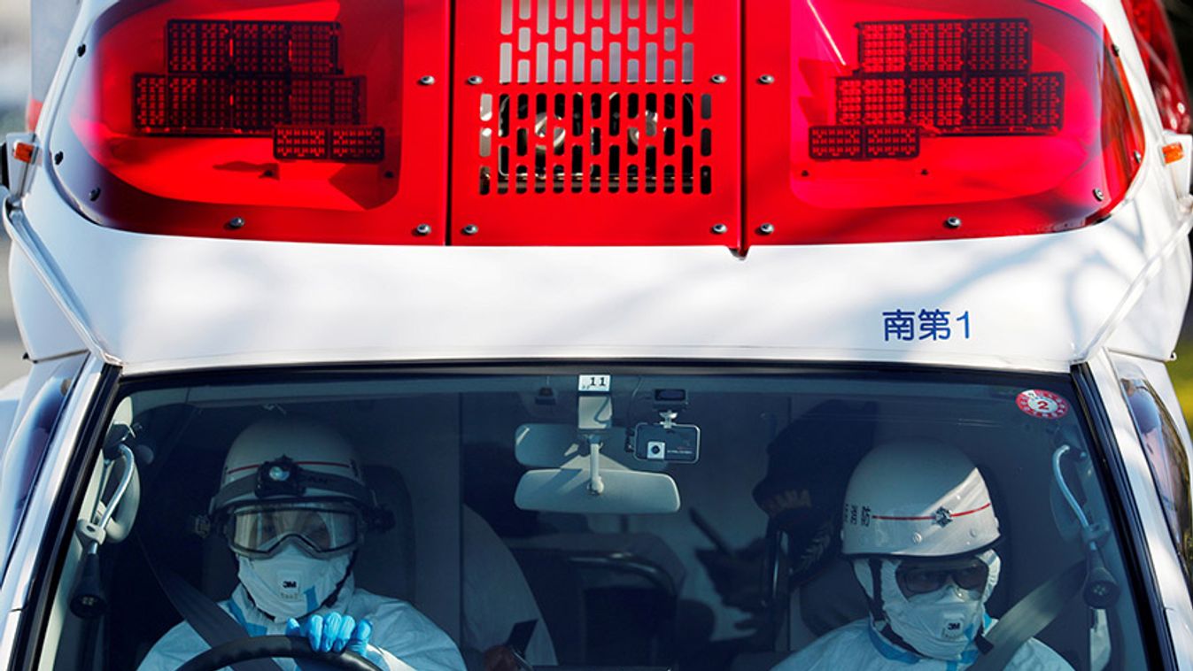 Ambulance workers in protective gears drive an ambulance which is believed to be carrying a person who was transferred from cruise ship Diamond Princess after ten people were tested positive for coronavirus, at a maritime police's base in Yokohama