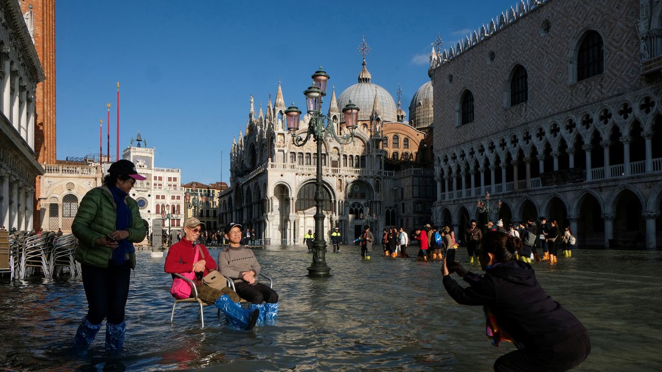 Tourists take pictures in the flooded St. Mark's Square during a period of seasonal high water