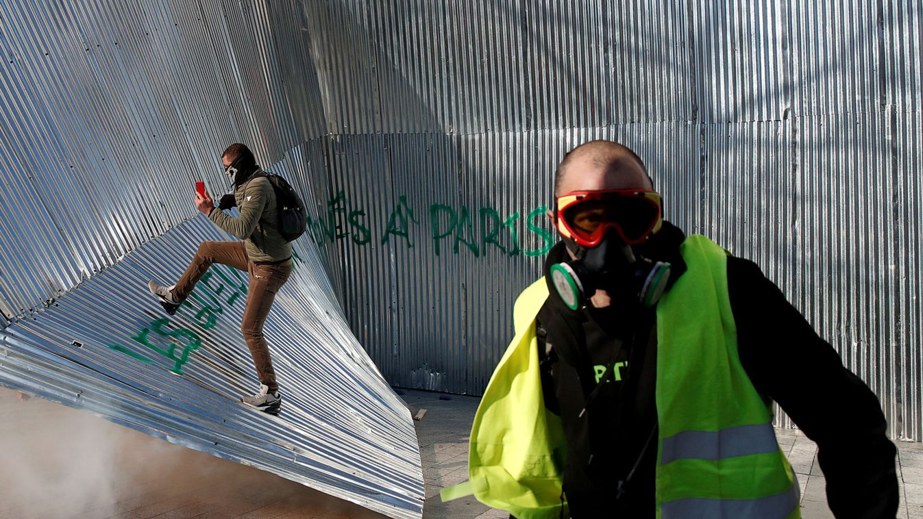 Protester wearing a yellow vest walks in front of demolished metal fencing during a demonstration by the "yellow vests" movement in Paris