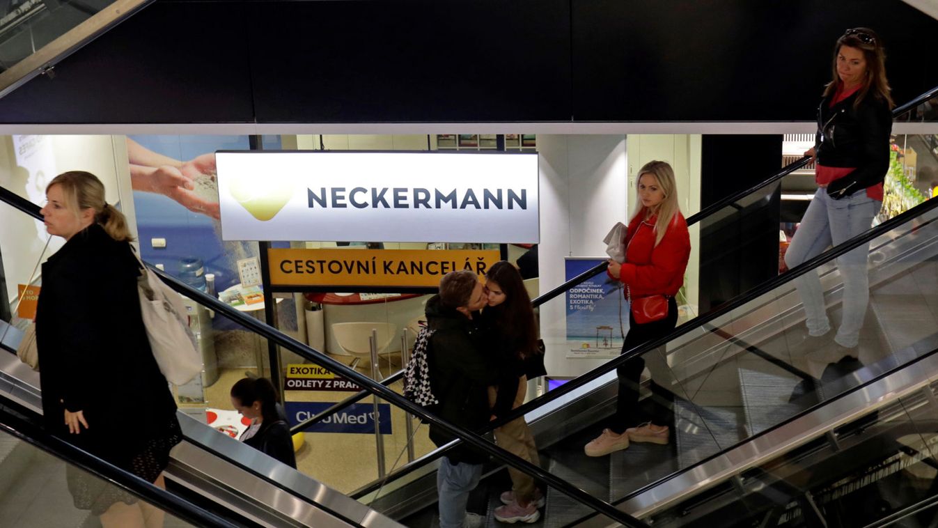 People use escalators next to a branch of Neckermann travel agency in Prague