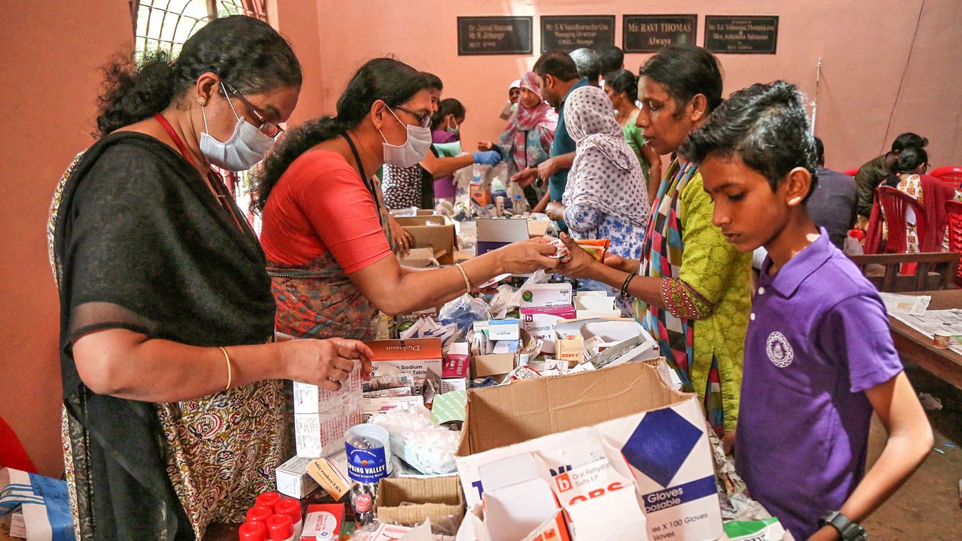 Flood-affected people receive free medicines inside a college, which has been converted into a temporary relief camp, in Aluva