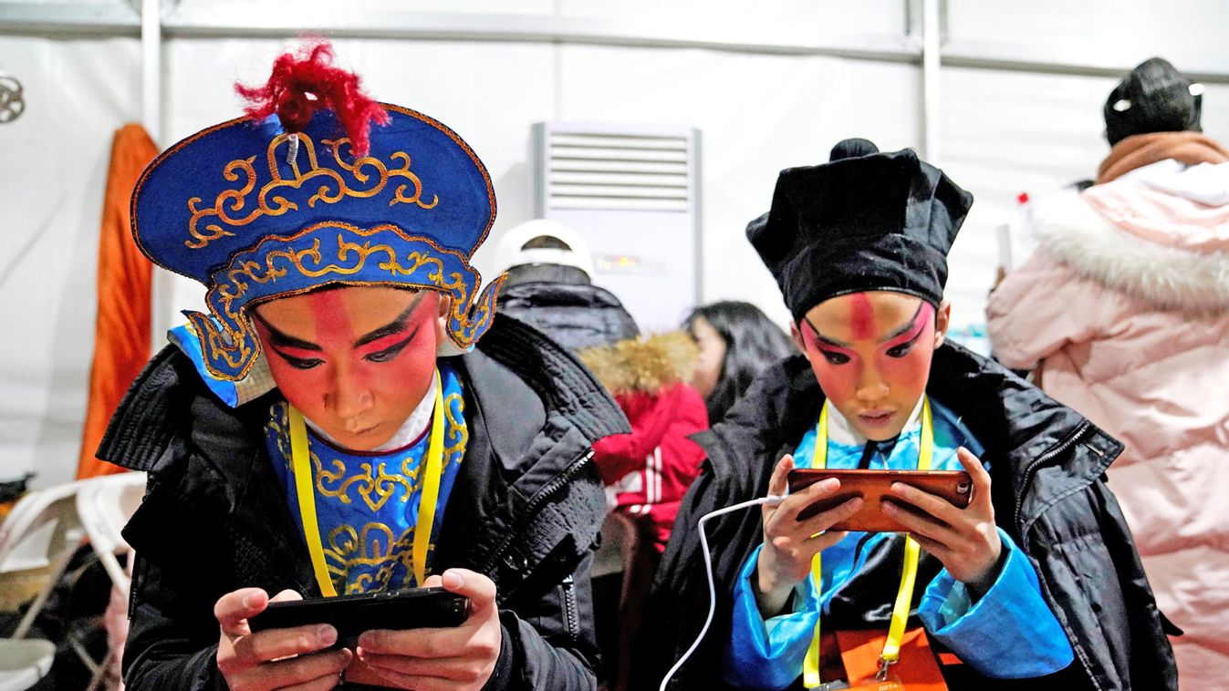 Beijing Opera performers play with their mobile phones ahead of a countdown event celebrating the new year in Beijing