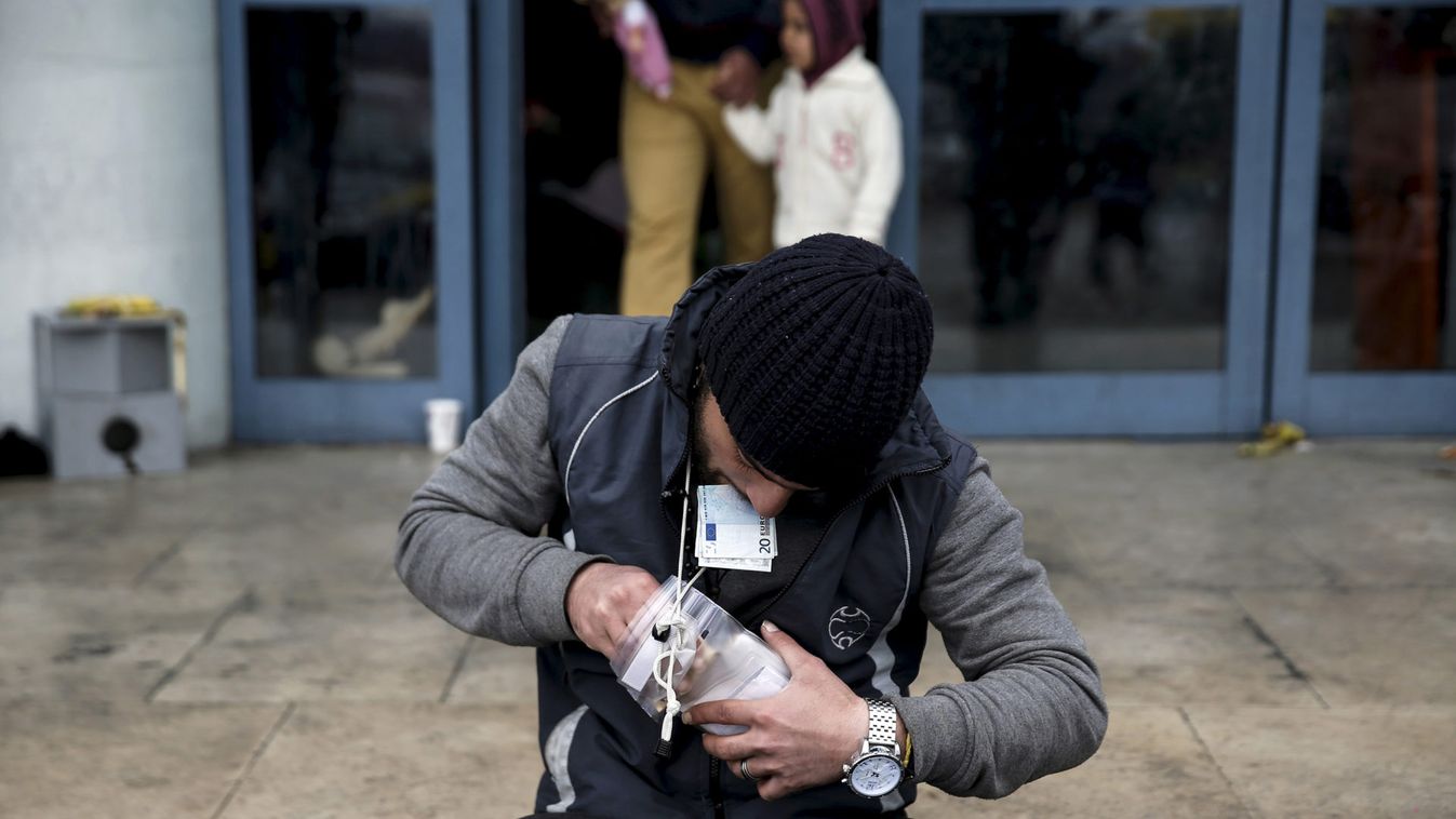 A refugee arranges his money outside a passenger terminal where stranded refugees and migrants find shelter at the port of Piraeus, near Athens
