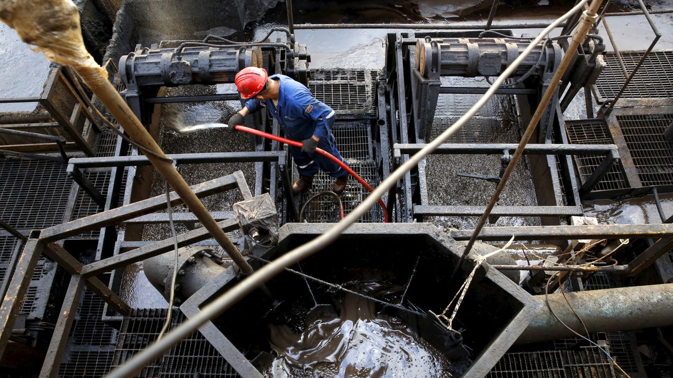 The flow of drilling mud is seen in a container while an oilfield worker works on a drilling rig at an oil well operated by Venezuela's state oil company PDVSA, in the oil rich Orinoco belt, near Cabrutica at the state of Anzoategui