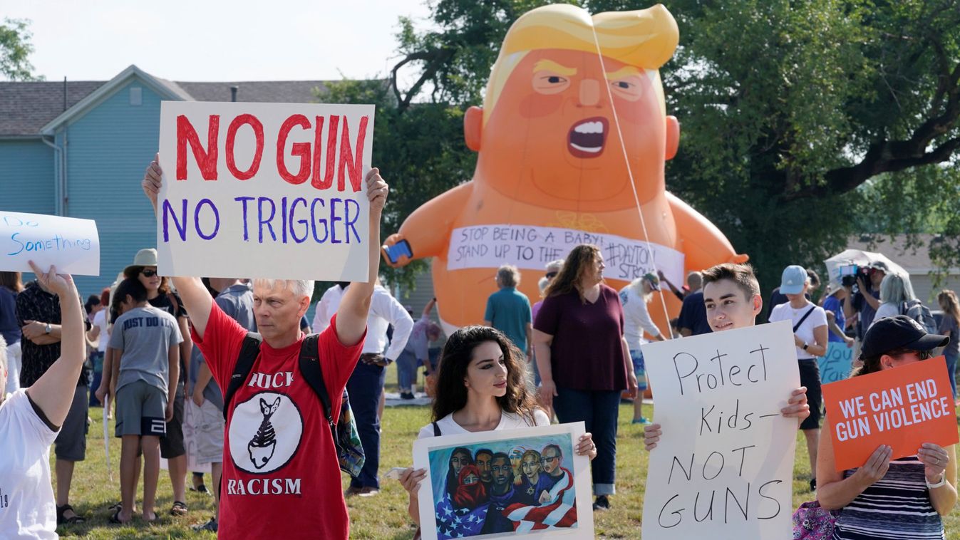 Protestors gather around a baby Trump balloon to voice their rally against gun violence and a visit from U.S. President Donald Trump following a mass shooting in Dayton