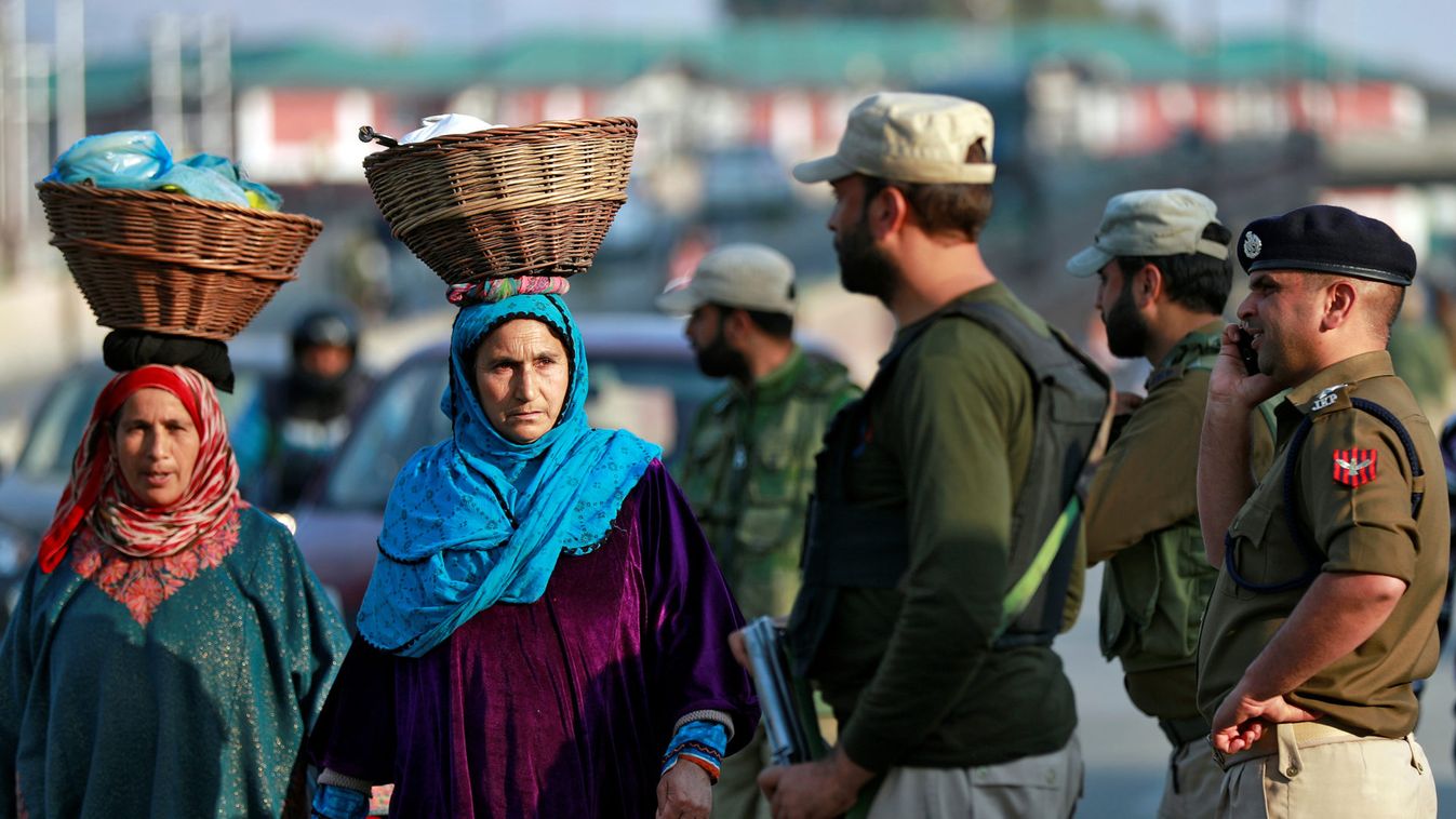 Kashmiri women walk past Indian policemen standing guard in a street in Srinagar