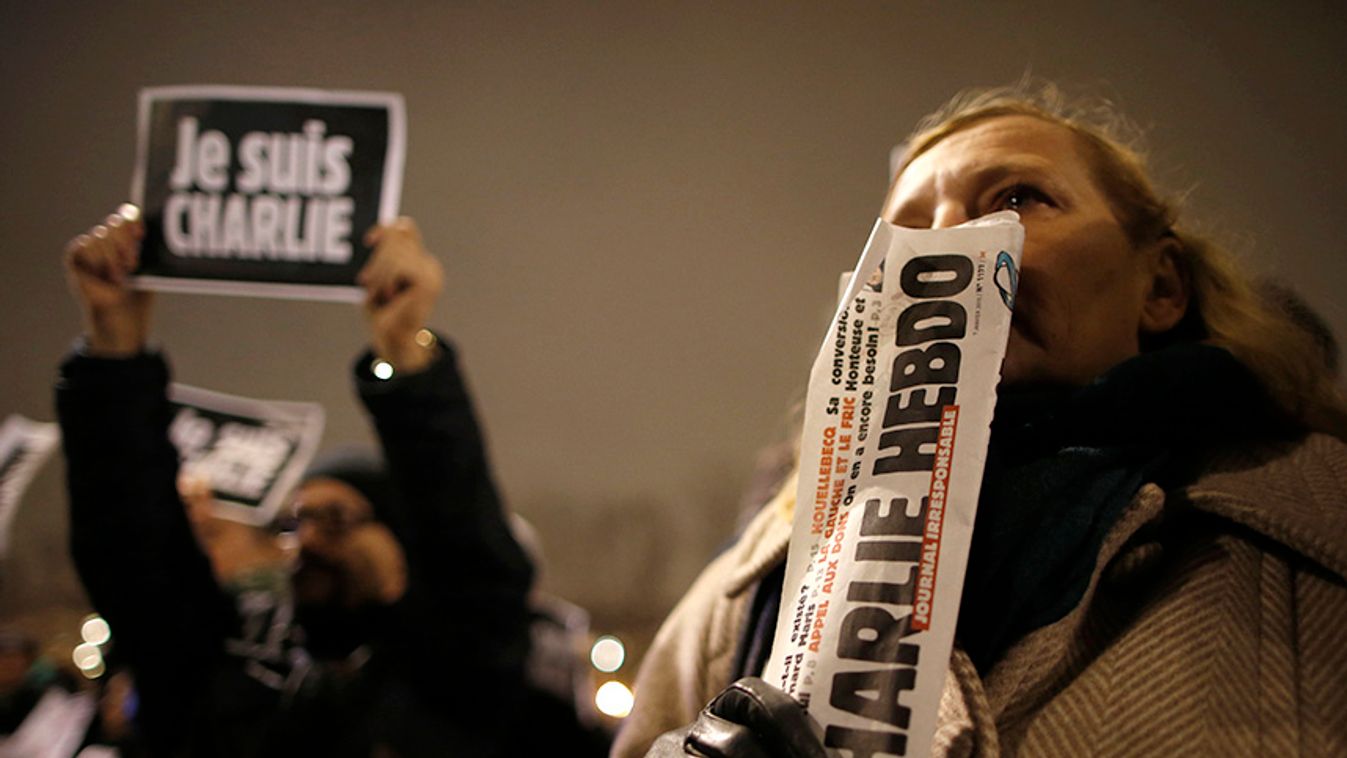 A man holds a copy of weekly satirical magazine Charlie Hebdo to pay tribute during a gathering at the Place de la Republique in Paris
