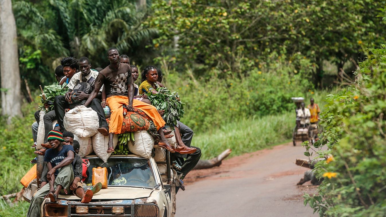 People sit on a car as they drive near Bangui