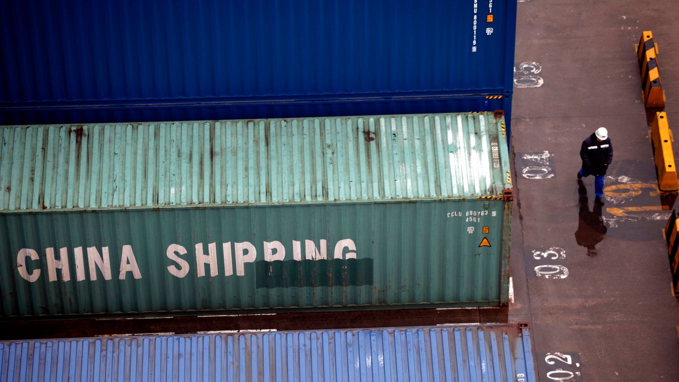 A worker walks past shipping containers at the Port of Shanghai