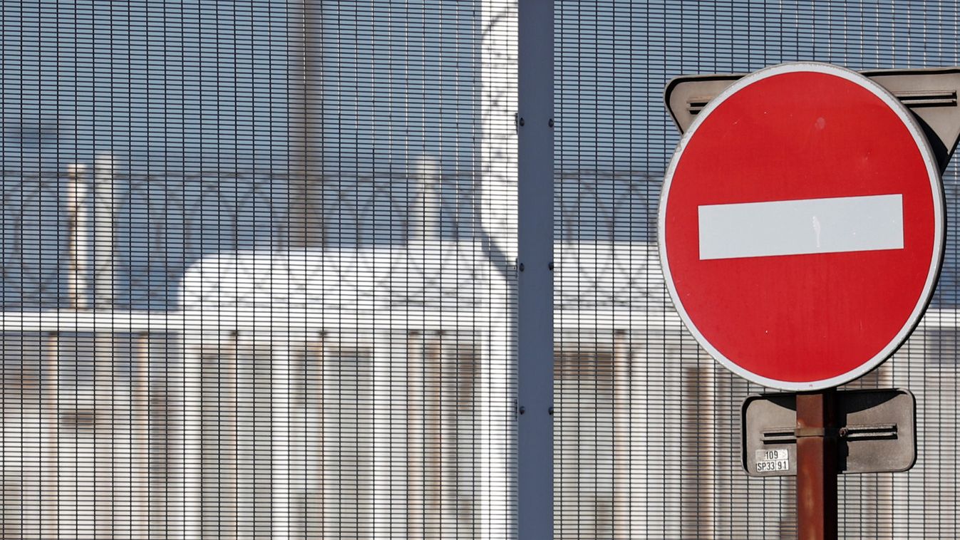 A migrant stands in front of the fencing of Calais Port