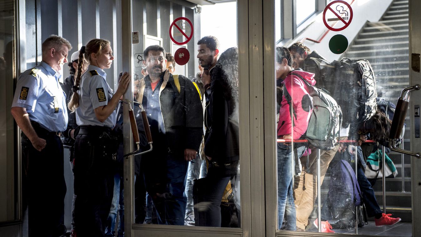 Migrants arrive at Rodby in Denmark, as Danish police guide them into a building at the harbour