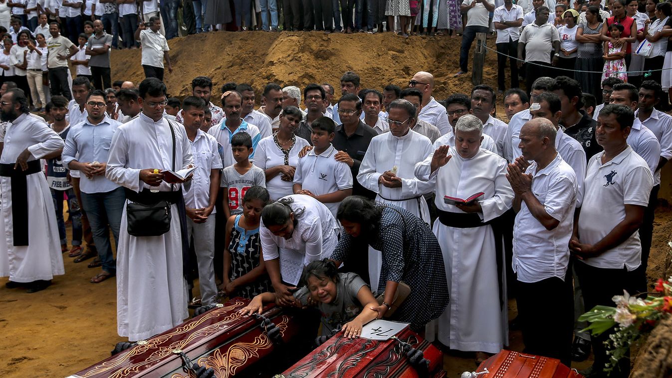 A woman reacts next to two coffins during a mass burial of victims, two days after a string of suicide bomb attacks on churches and luxury hotels across the island on Easter Sunday, at a cemetery near St. Sebastian Church in Negombo