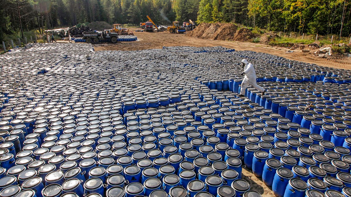 A Belarussian Emergency Ministry worker walks on barrels of pesticide at a burial site in a forest near the village of Savichi