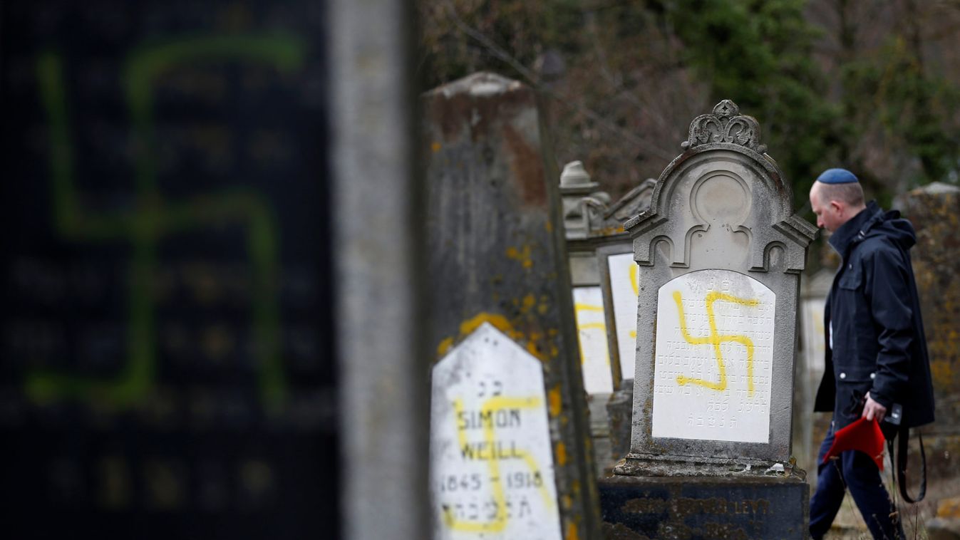 A man walks near graves that were desecrated with swastikas at the Jewish cemetery in Quatzenheim