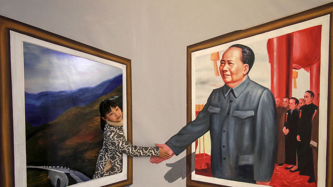 A girl poses for a photograph next to a 3D painting of China's late Chairman Mao Zedong at an exhibition in Binzhou, Shandong province