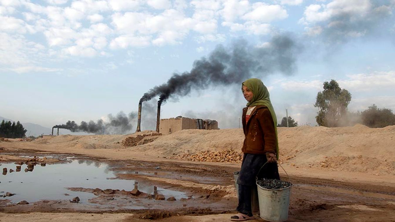 Aisha carries coal to be used for cooking and heating from a brick-making factory in Jalalabad