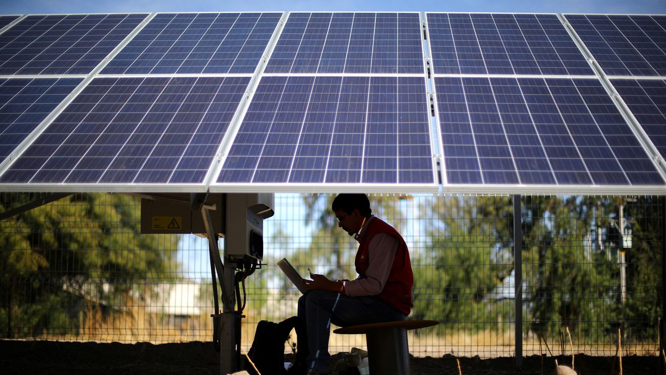 An engineer works under solar panels at a solar plant near Santiago,