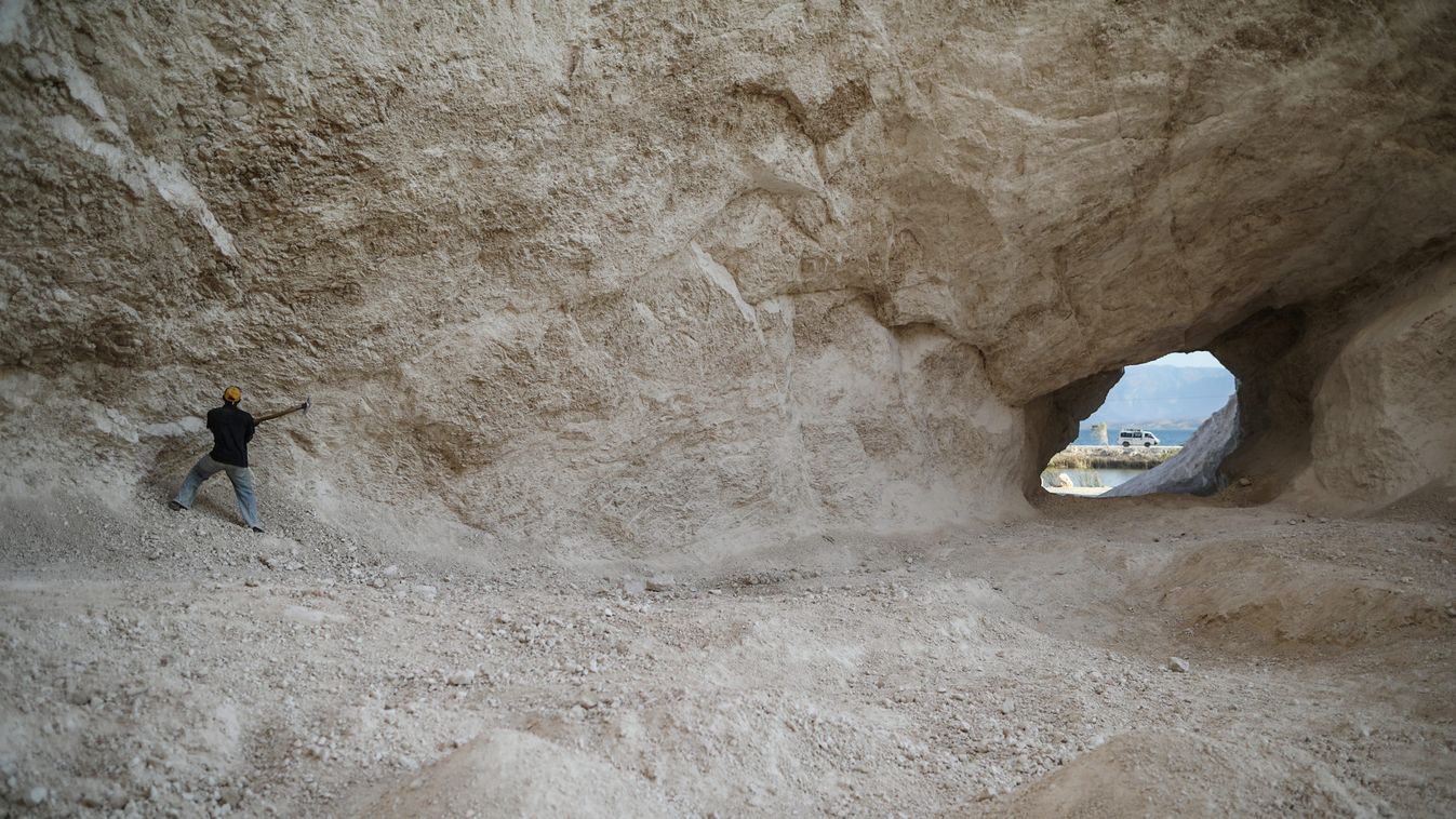 A man uses a pick to break rocks and get sand in a sand mine on the outskirts of Fond Parisien