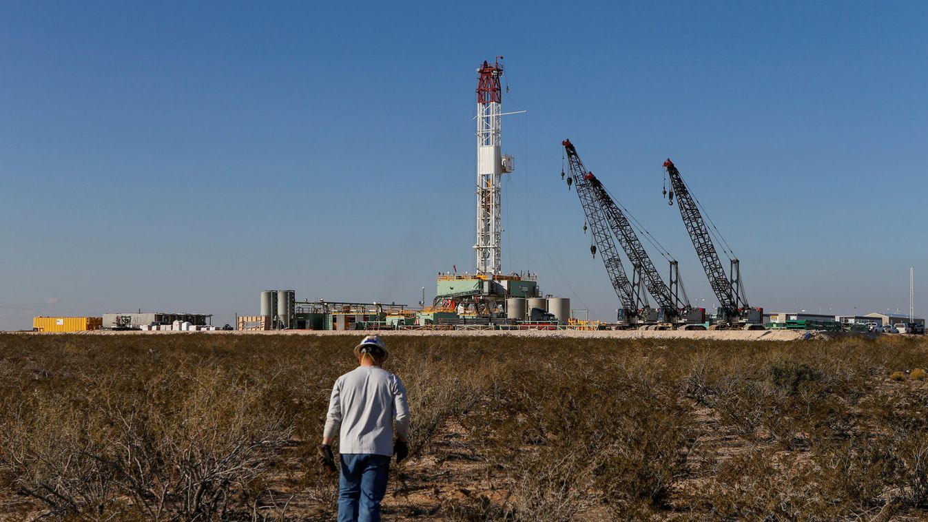 An oil worker walks towards a drill rig after placing ground monitoring equipment in the vicinity of the underground horizontal drill in Loving County