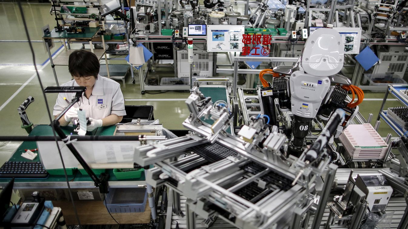 A humanoid robot works side by side with an employee in the assembly line at a factory of Glory Ltd., a manufacturer of automatic change dispensers, in Kazo, north of Tokyo
