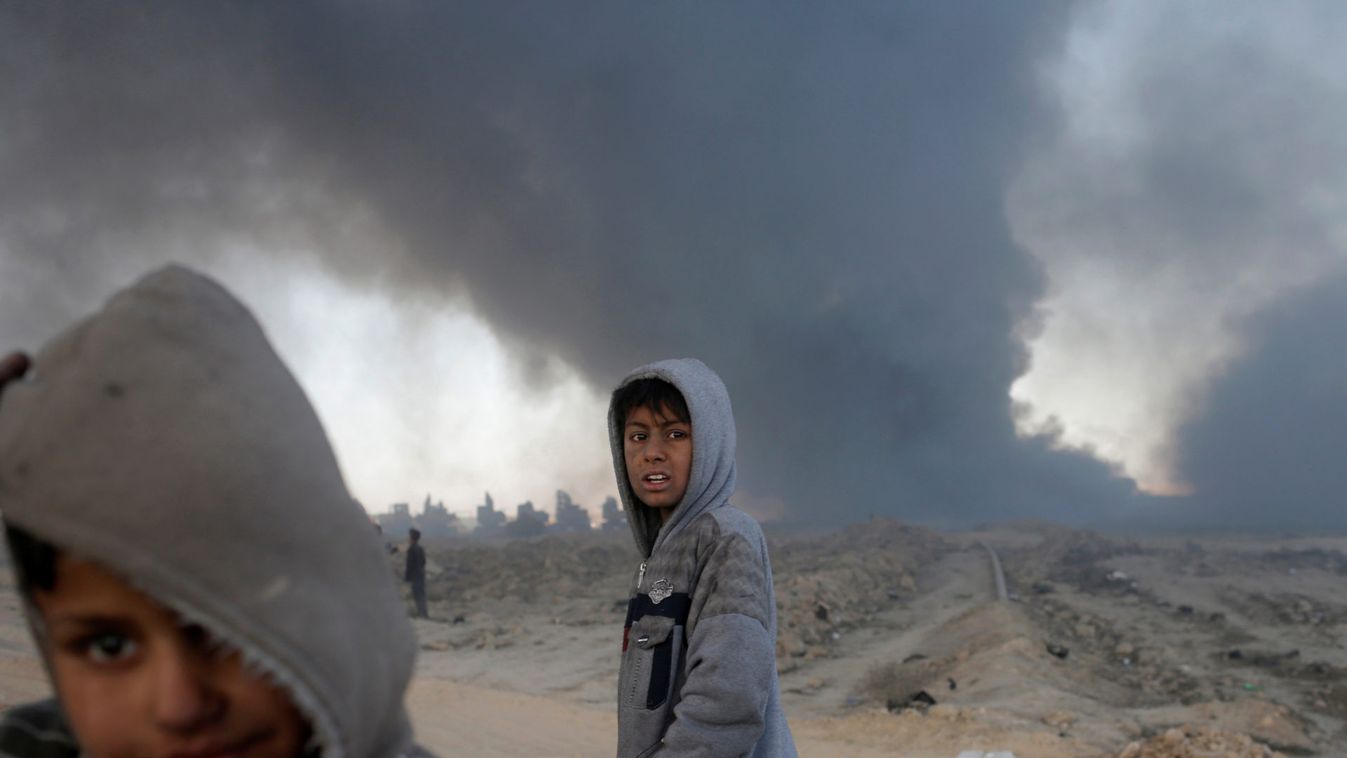 Boys stand in front of oilfields burned by Islamic State fighters in Qayyara