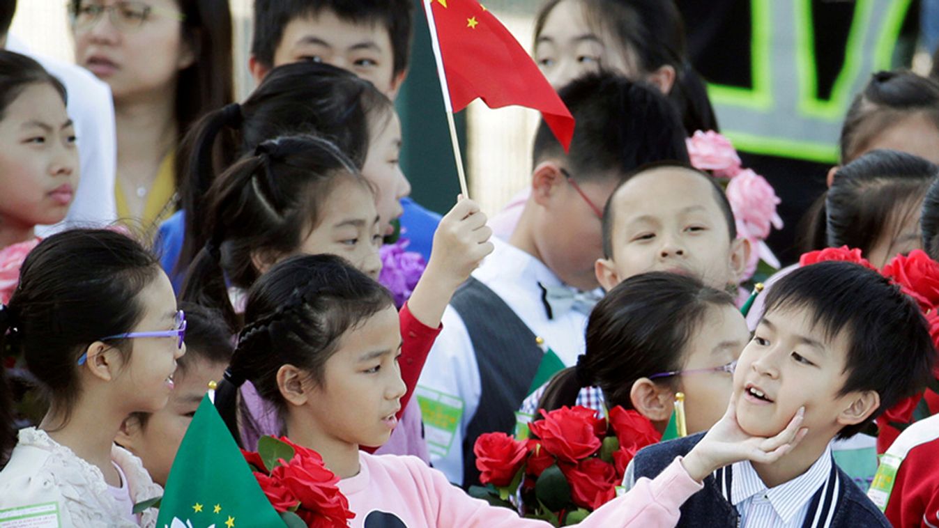 Children holding Chinese and Macau flags get ready before Chinese President Xi Jinping's arrival at Macau International Airport in Macau