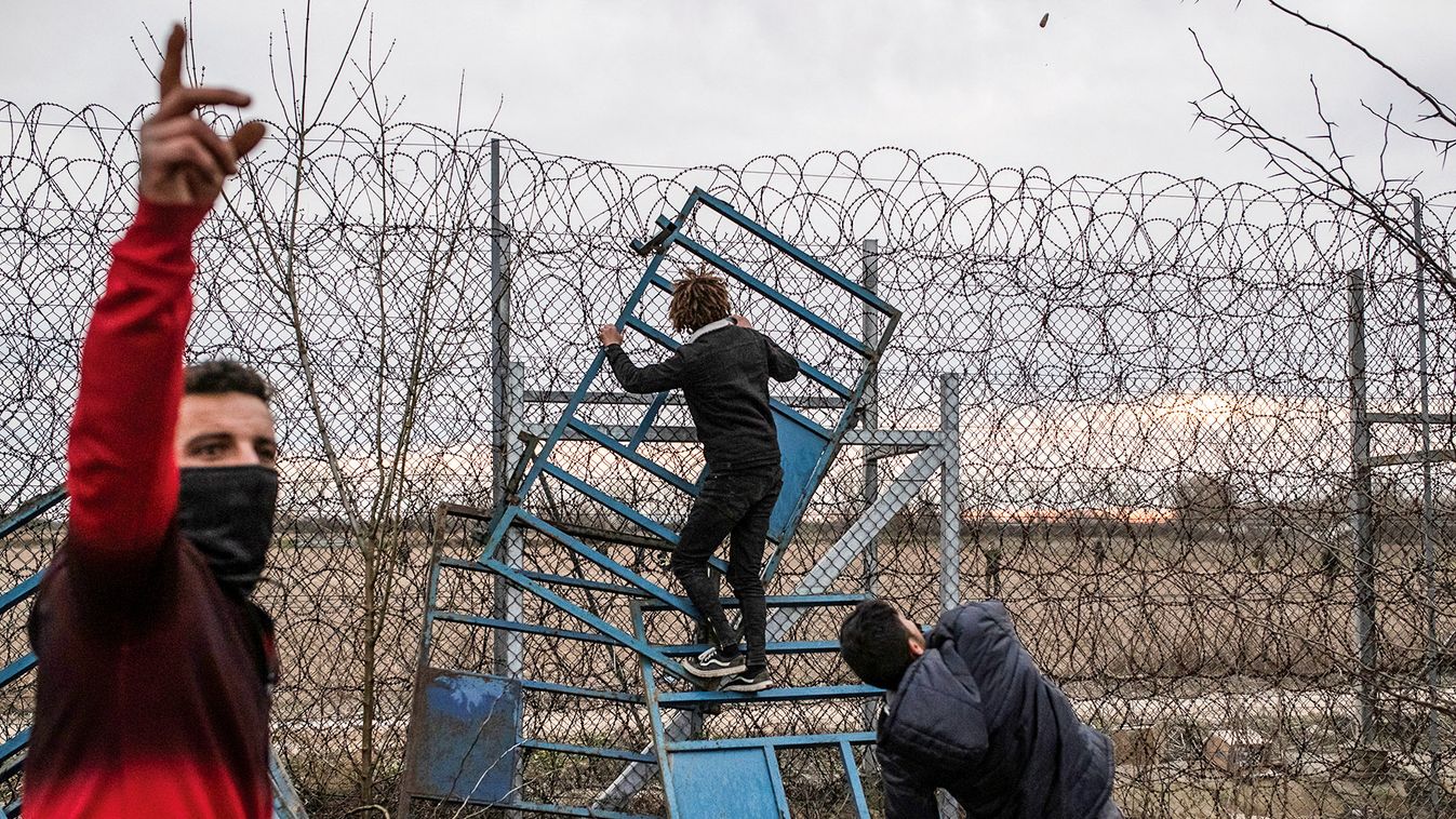 Migrants climb fence at the border as they clash with Greek riot police at Turkey's Pazarkule border crossing with Greece's Kastanies, near Edirne