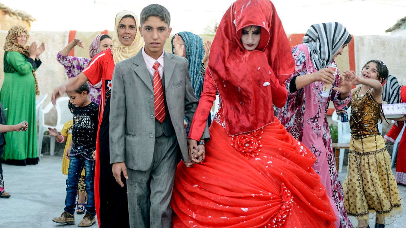 Hussein Younis Ali, 14 walks with his bride Nada Ali Hussein, 17, during wedding party at his home in Tikrit