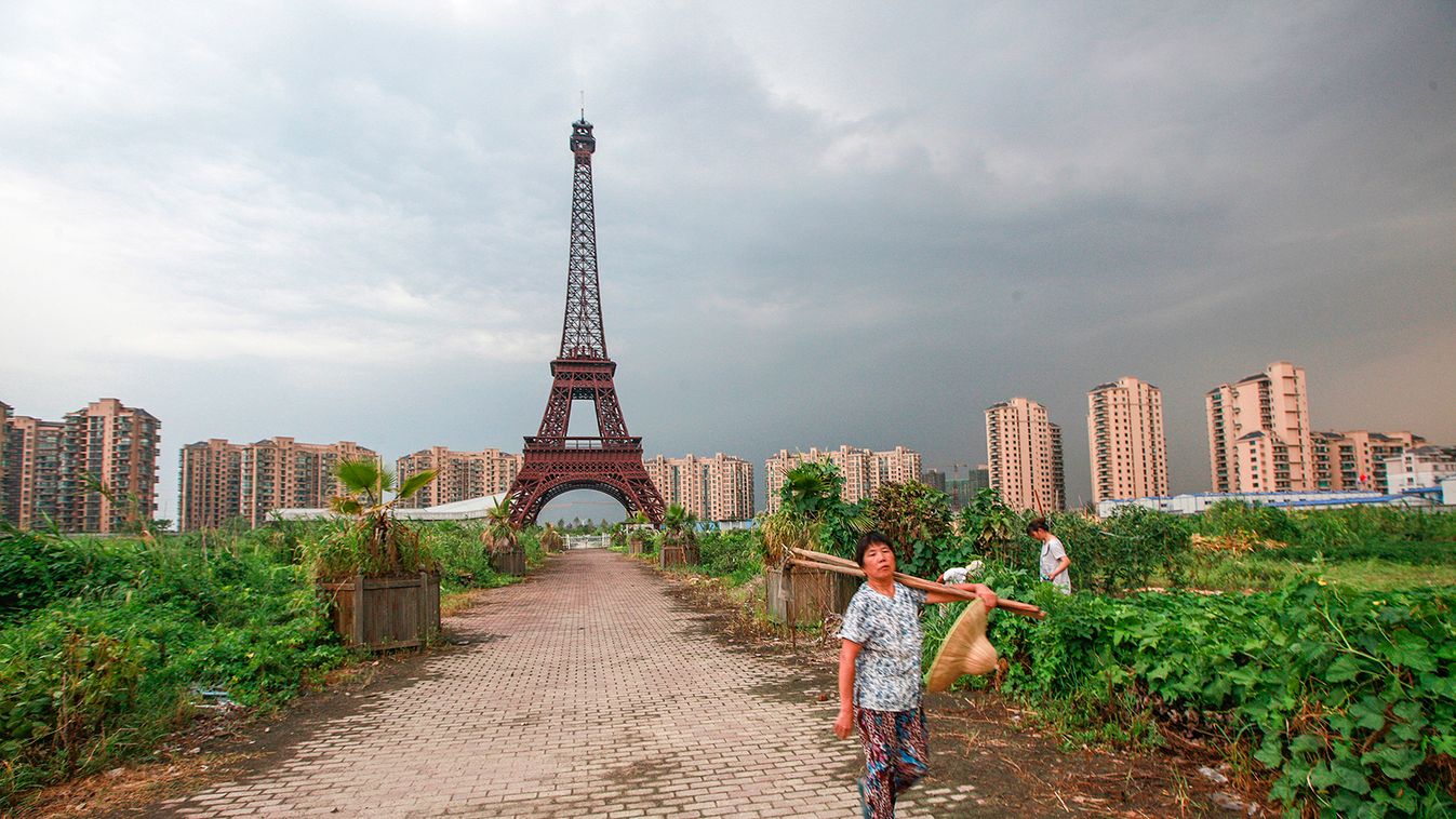 Farmer walks down dirt road under a replica of Eiffel Tower at the Tianducheng development in Hangzhou