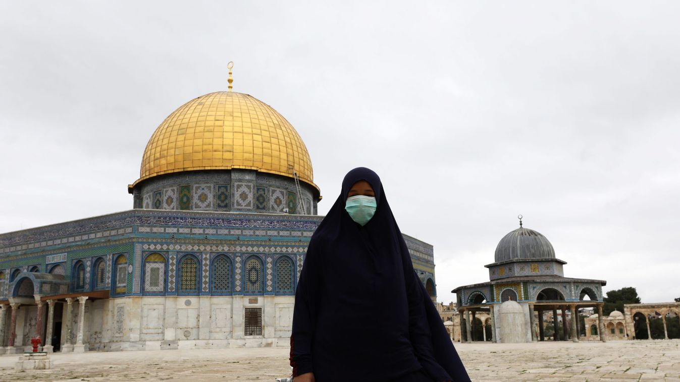 A worshipper wearing a mask walks in front of the Dome of the Rock in the compound known to Muslims as Noble Sanctuary and to Jews as Temple Mount, in Jerusalem's Old City