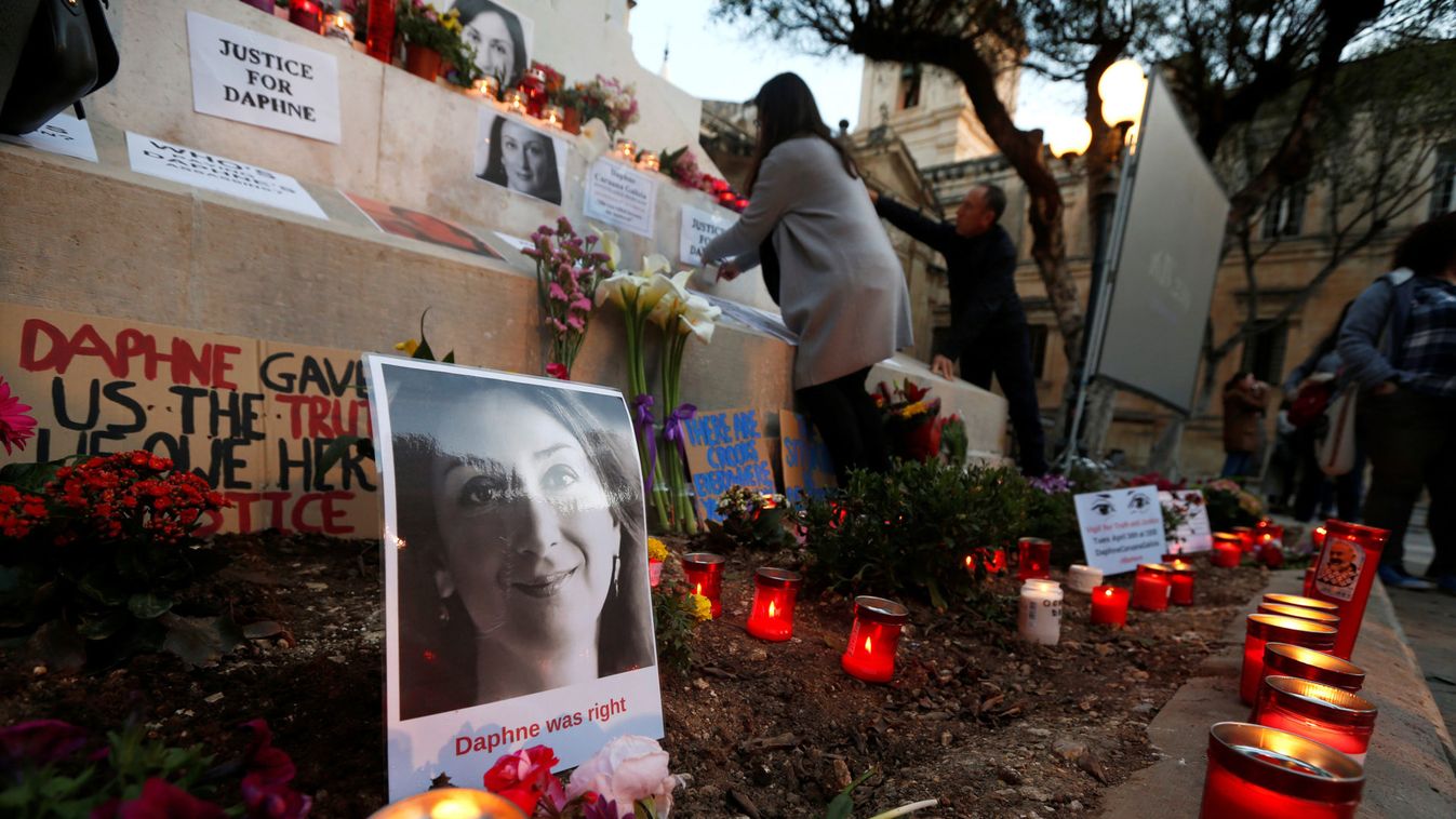 People light candles and place flowers on a makeshift memorial during a protest and vigil marking eighteen months since the assassination of anti-corruption journalist Daphne Caruana Galizia outside the Courts of Justice in Valletta