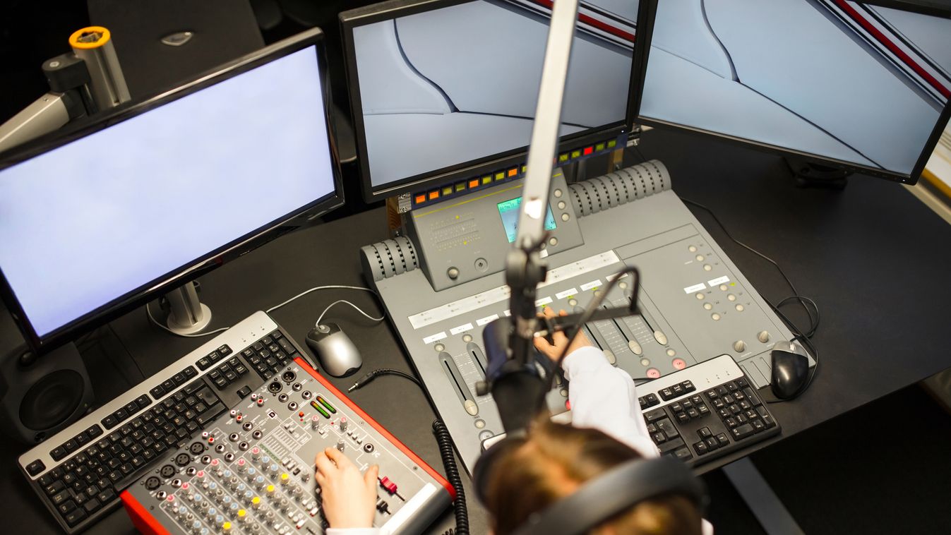 Female Jockey Using Music Mixers And Screens In Radio Studio