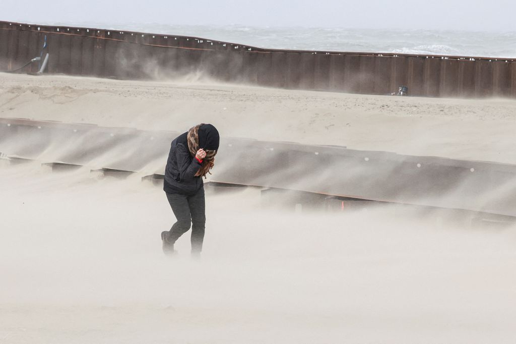 A person walks as waves break on the beach in the wake of Storm Eunice in Blankenberge, Belgium, February 18, 2022. REUTERS/Yves Herman  REFILE - CORRECTING CITY