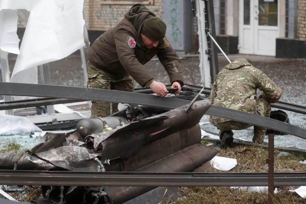 Police officers inspect the remains of a missile that landed in the street in Kyiv