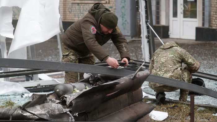 Police officers inspect the remains of a missile that landed in the street in Kyiv