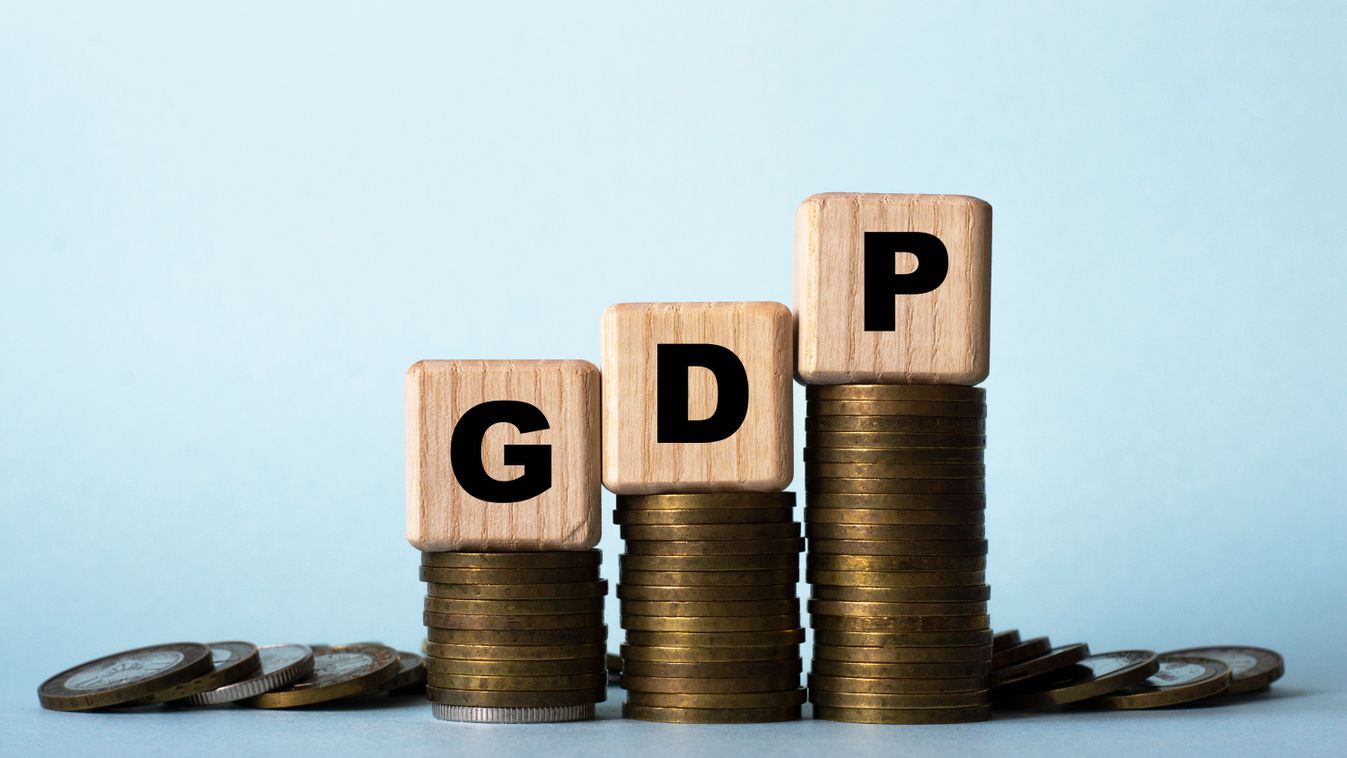 GDP
 - acronym on wooden cubes. Which stand on stacks of coins on a light background