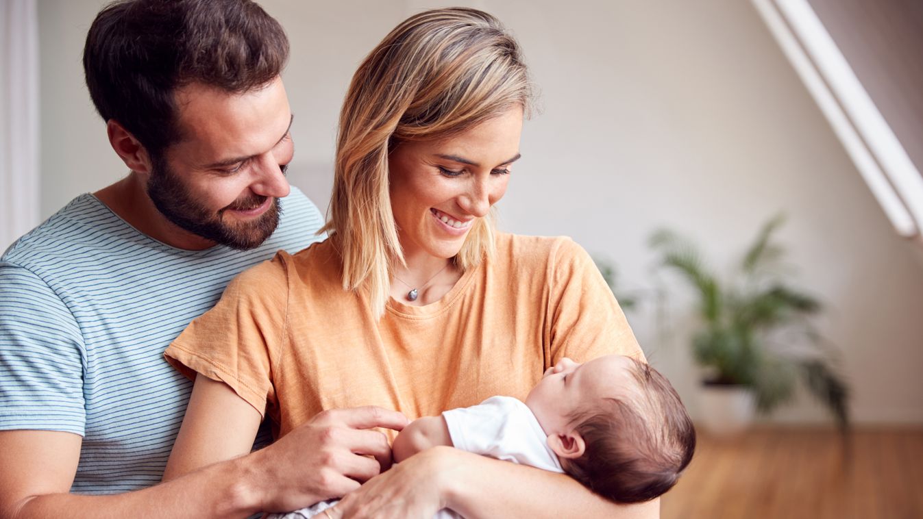 Loving Parents Holding Newborn Baby At Home In Loft Apartment