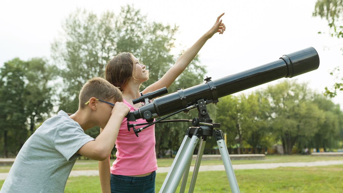 Children teenagers with telescope look at the sky in nature