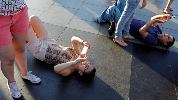 Tourists lie on the floor to take pictures at the Redeeming Christ atop the Corcovado mountain in Rio de Janeiro