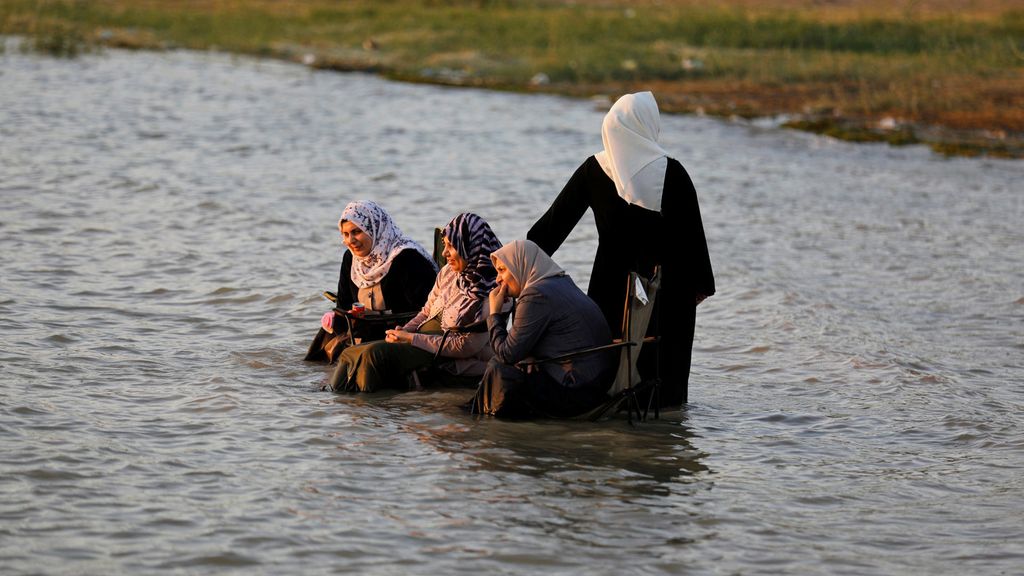 Women sit in chairs in the water at Lake Habbaniyah
