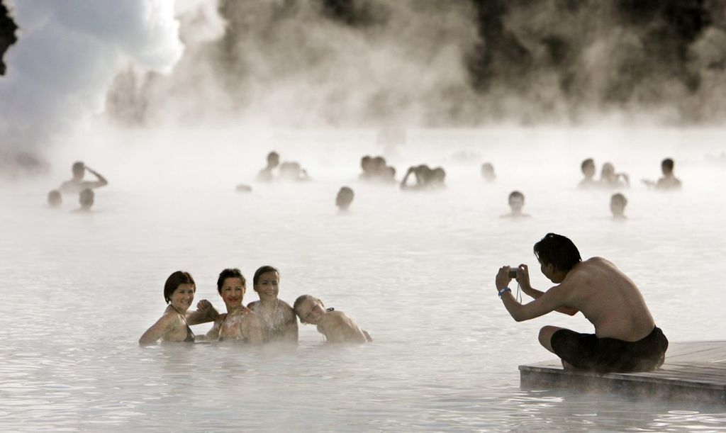 Bathers pose for a photo as they swim in the geothermal hot springs at Iceland's Blue Lagoon near Grindavik