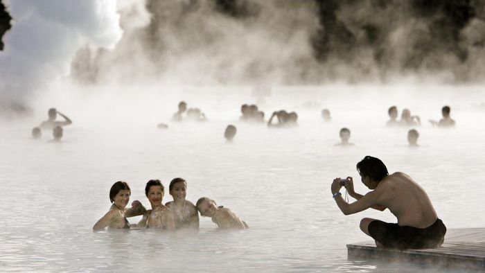 Bathers pose for a photo as they swim in the geothermal hot springs at Iceland's Blue Lagoon near Grindavik