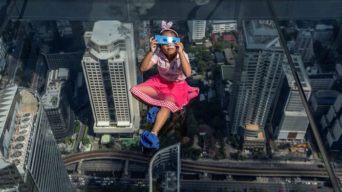 People observe a partial solar eclipse in Bangkok